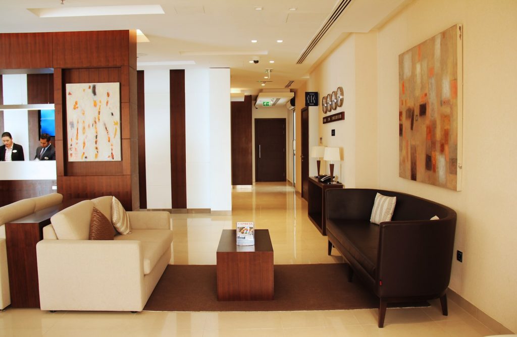 Interiors of Tulip Inn Hotel. Two sofas on the foreground with a coffe table in between. Reception on the background.