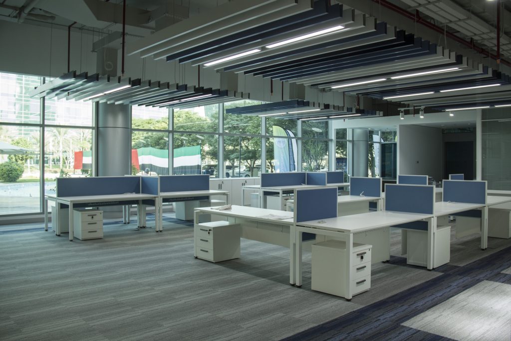 Interiors of Jafza 17 office. There are white desks in a room with a big stained glass wall