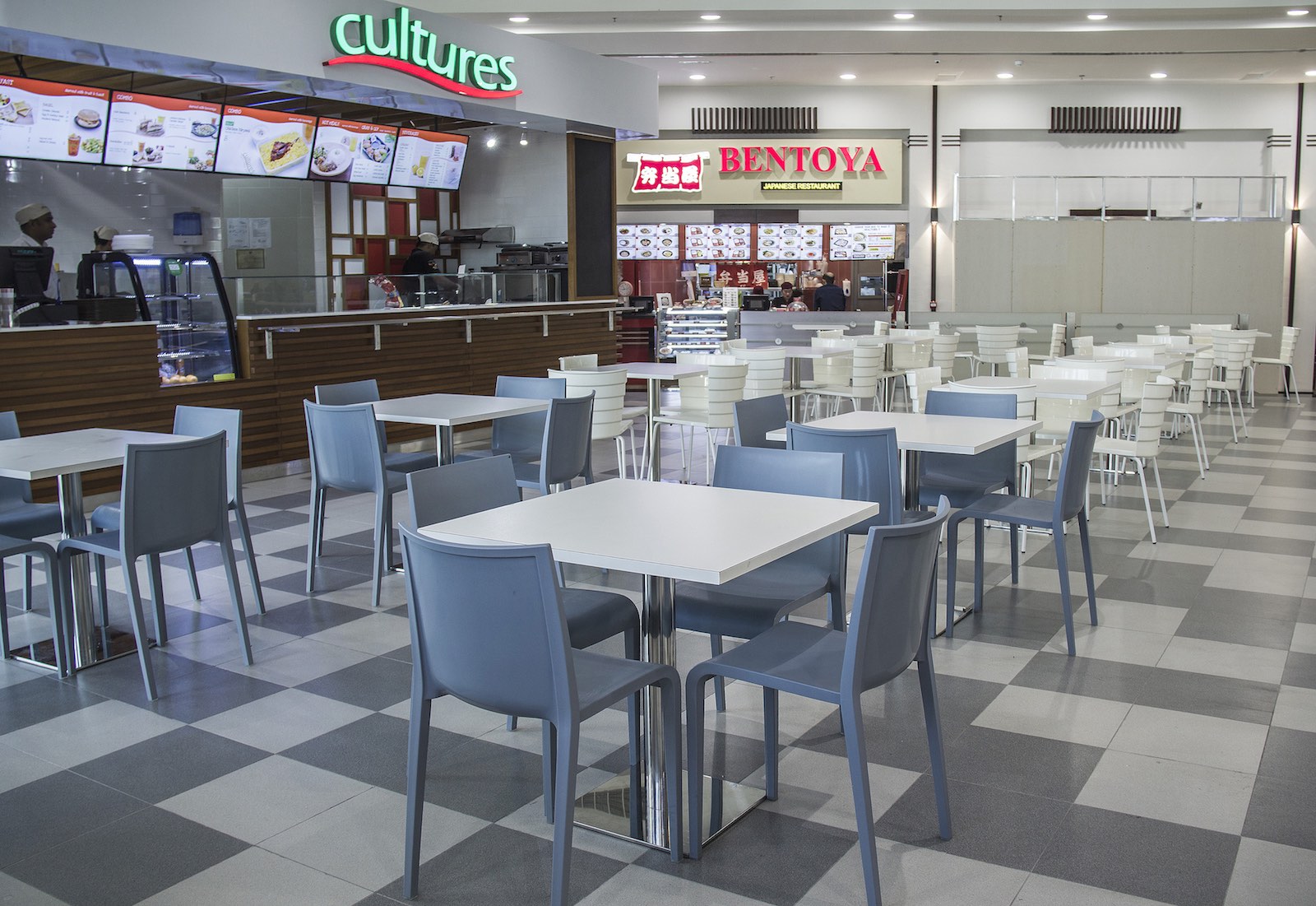 Tables and chairs of Jafza food court 15 with restaurants on the background