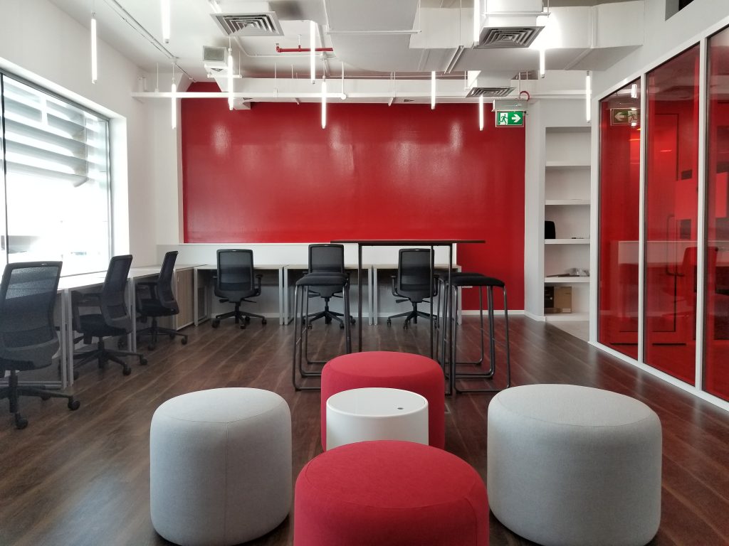 Four Principles office dubai. There are puff on the foreground and chairs with L-shape table on the background. This are "Four Principles" offices